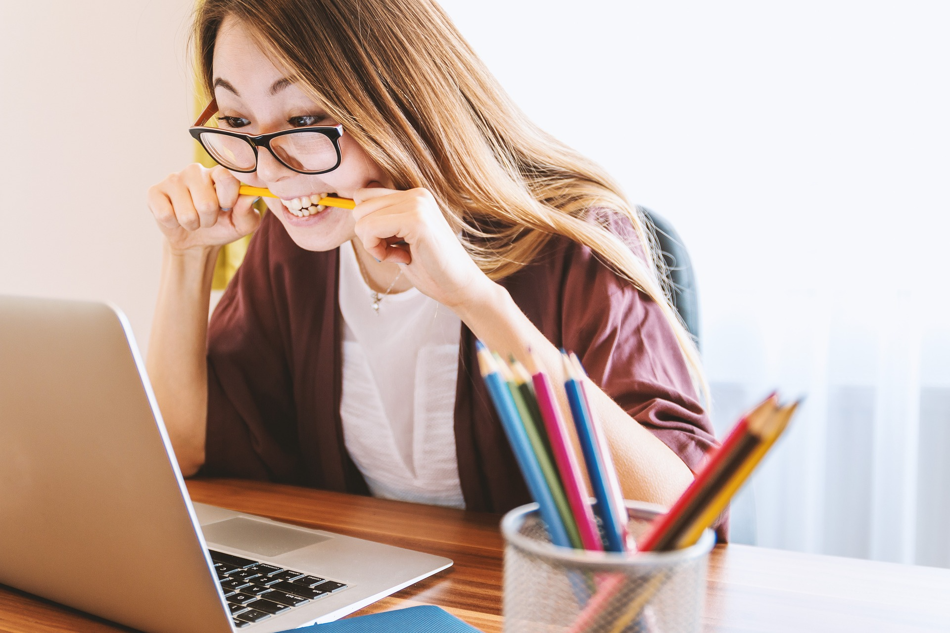 image qui représente une jeune femme devant son ordinateur en train de croquer un crayon car est craque sous l'effet du stress